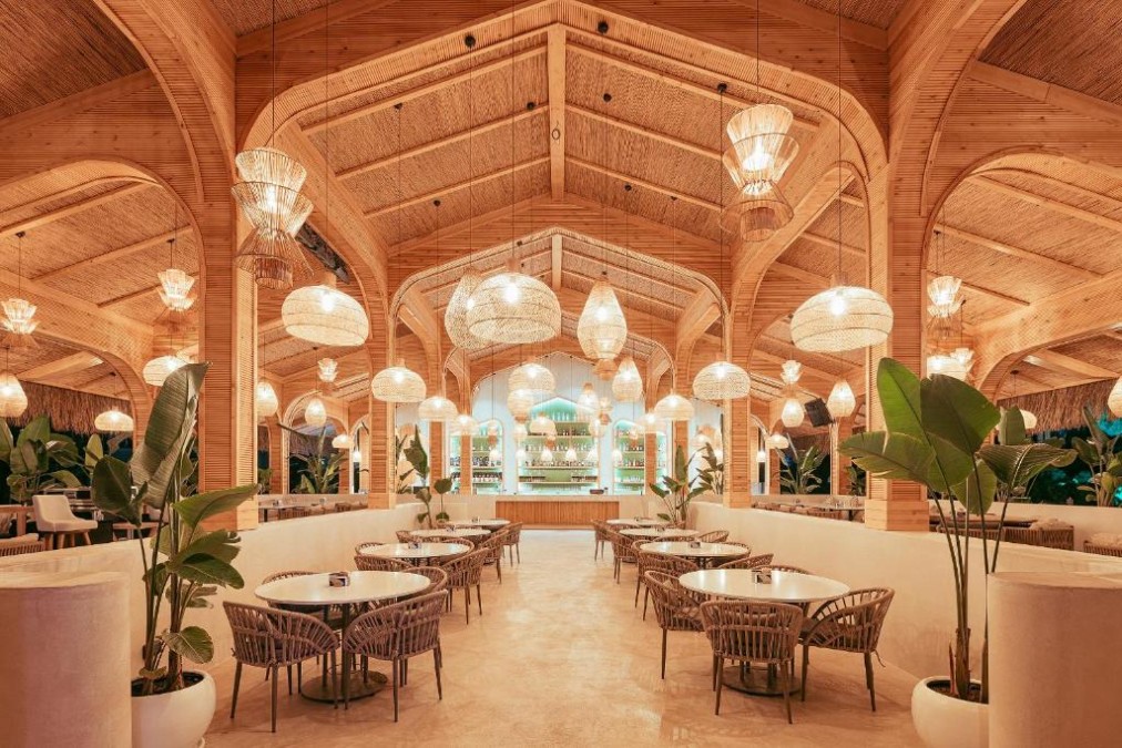 Stylish bar and lounge area with warm wooden architecture, woven pendant lights and tropical plants.