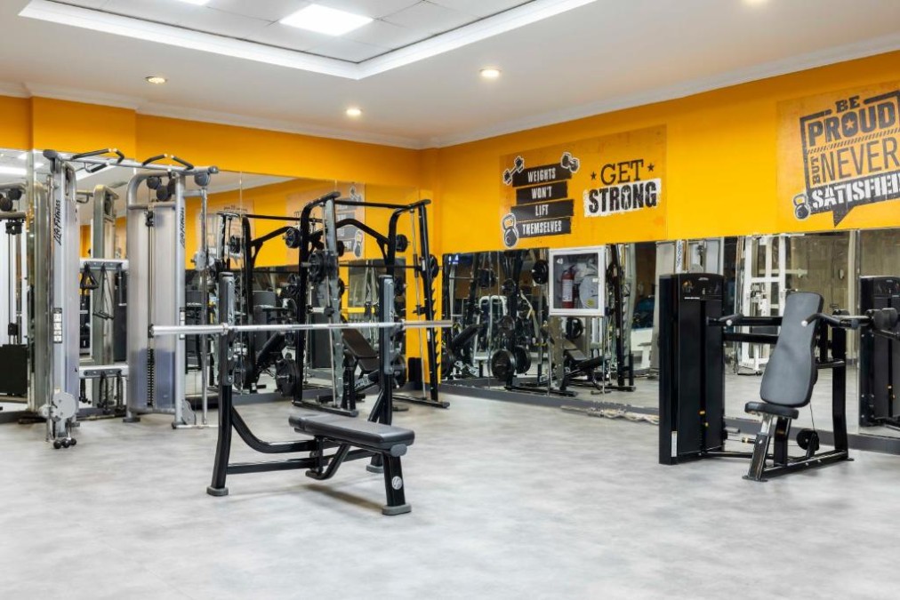 Gym area with cable stations, bench and mirrored wall.