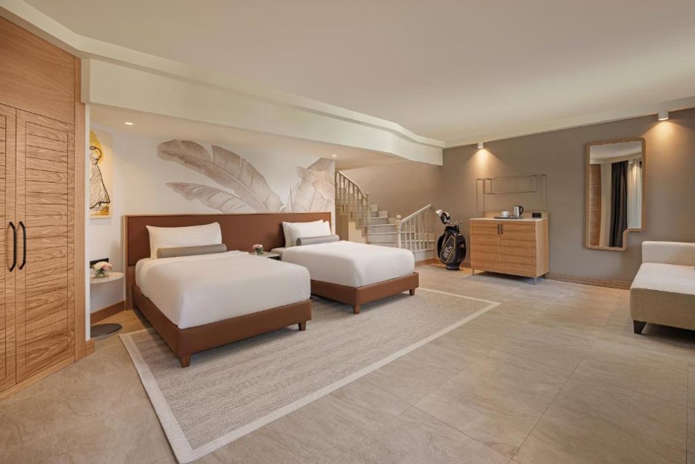 Spacious guest room with two beds, seating area, staircase and golf-themed decor.