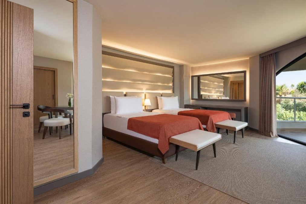 Spacious twin room with seating area, work table and balcony access.