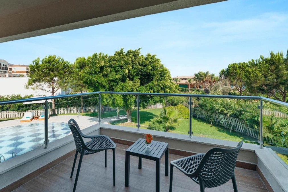 Balcony seating area overlooking garden and poolside surroundings.
