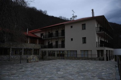 Resort exterior with stone courtyard and forested hillside surroundings.