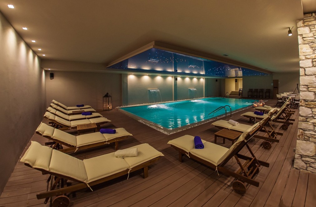 Indoor recovery pool with loungers, water features and low lighting.