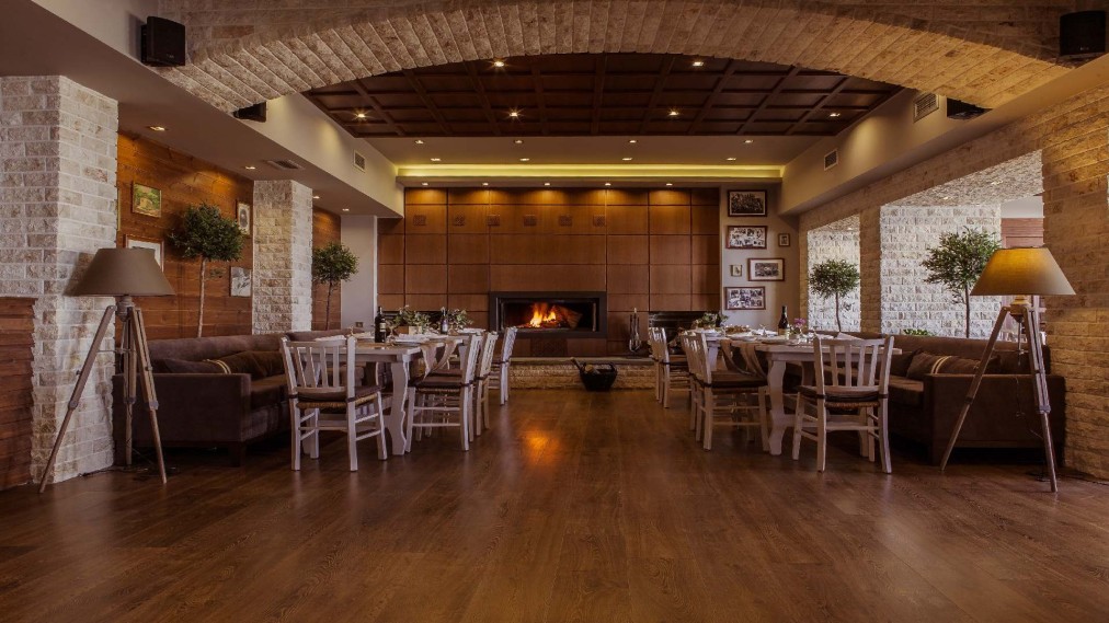 Restaurant dining room with fireplace, wooden floors and lounge seating.