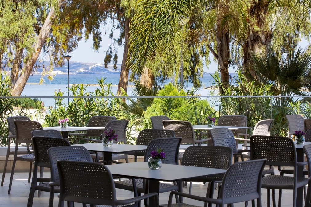 Outdoor dining area surrounded by greenery with tables overlooking the sea