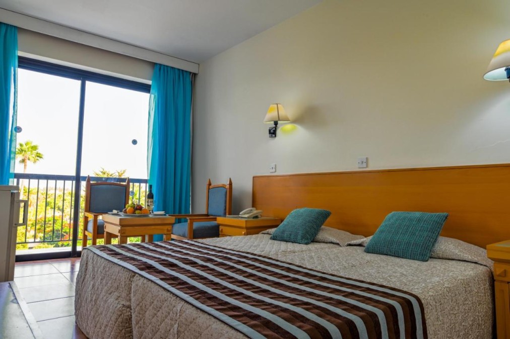 Guest room with double bed, balcony, chair and table by the window.
