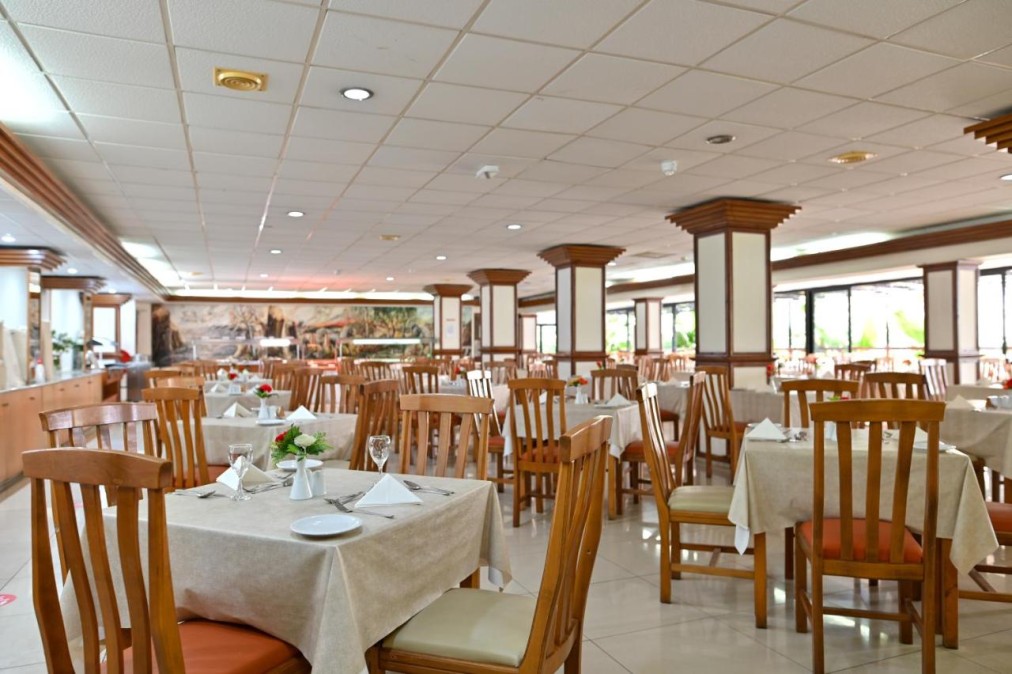 Restaurant dining room with set tables, wooden chairs and bright interior.