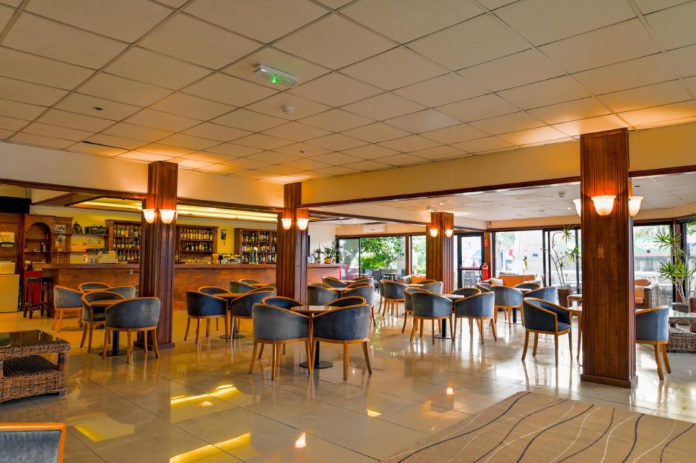 Hotel bar lounge with armchairs, wooden columns and large windows.