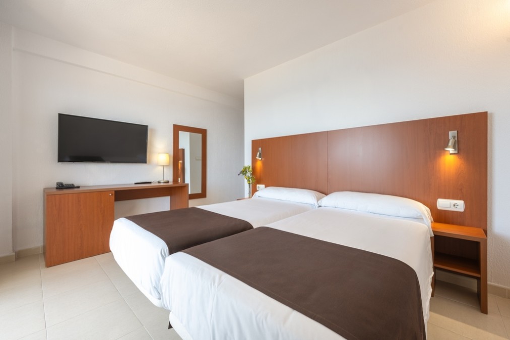 Twin room with two single beds, desk, TV and mirror.