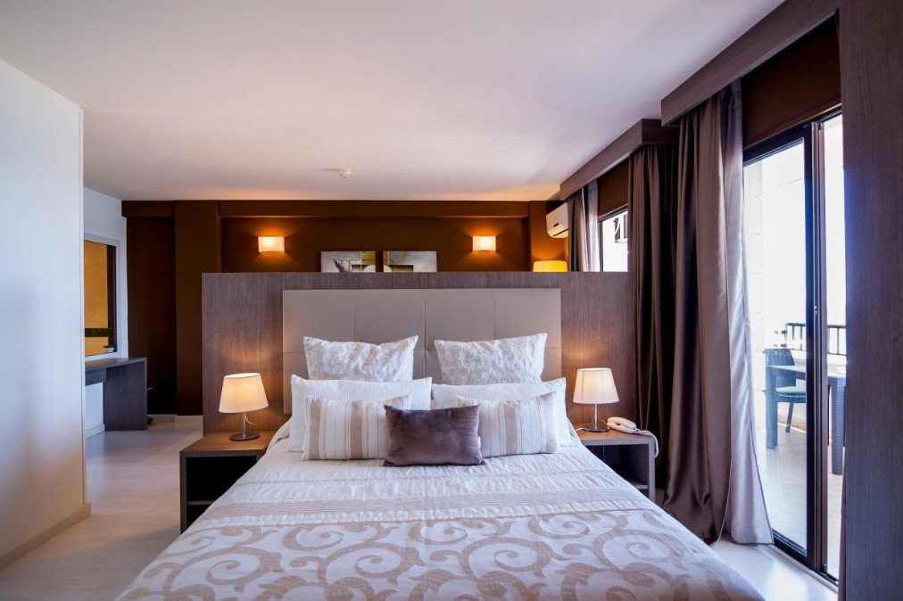 Bedroom with double bed, bedside lamps and balcony access.