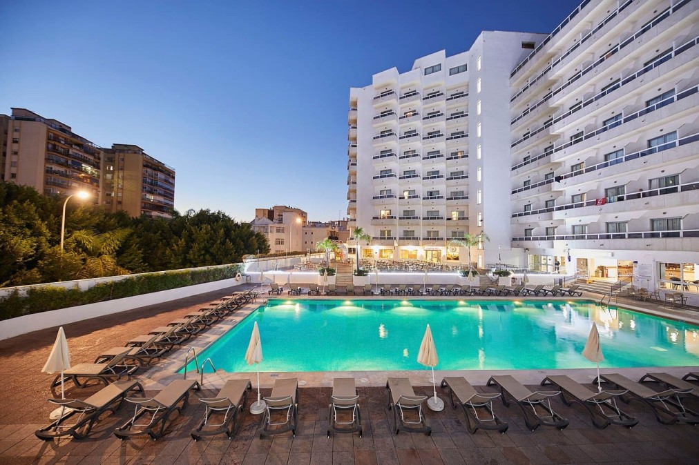 Outdoor pool with sun loungers and parasols, evening view