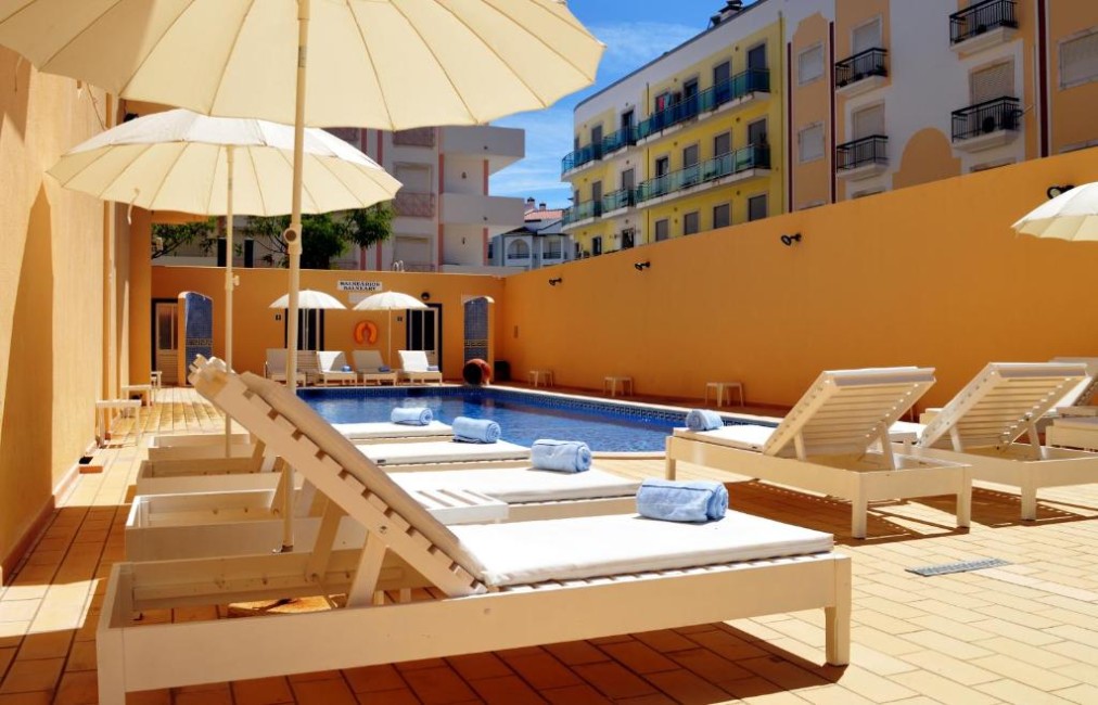 Sun loungers and umbrellas beside the outdoor pool in the courtyard.