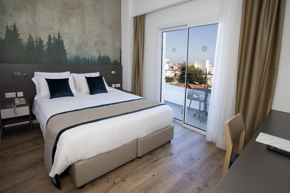 Double room with balcony doors, a forest mural wall, desk and city view.
