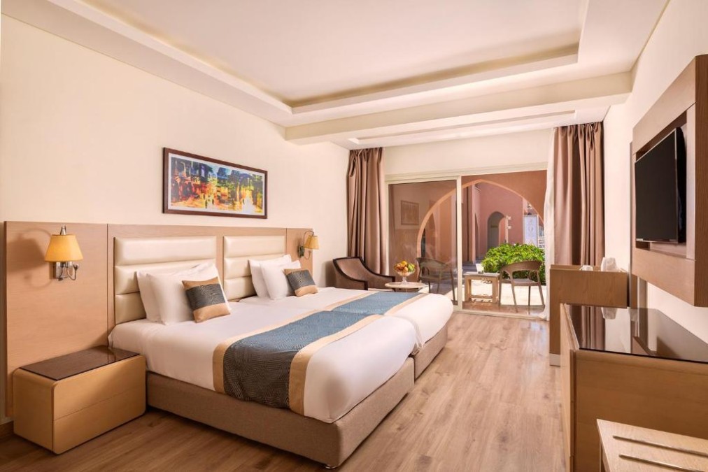 Bright hotel room with twin beds, artwork, and terrace access with outdoor seating