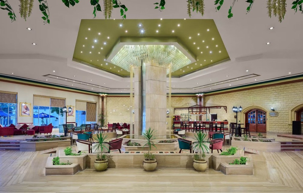 Elegant hotel lobby with central fountain, modern lighting, and seating area near a bar