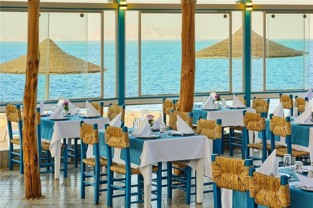 Seaside restaurant with blue chairs and white tablecloths, offering a view of the Red Sea