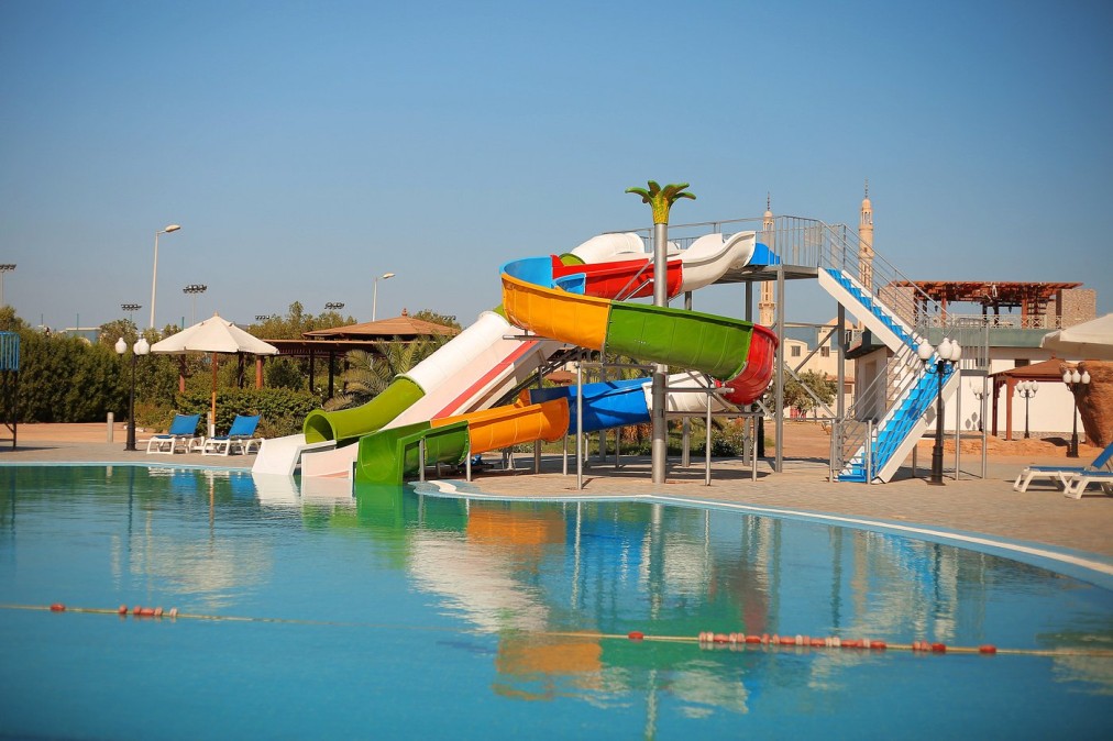 Outdoor pool area with colorful water slides and lounge chairs, ideal for athlete relaxation after training