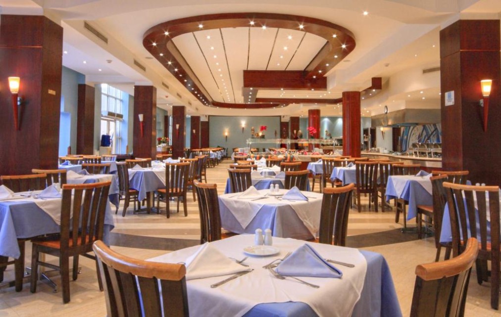 Spacious dining hall with wooden chairs, blue tablecloths, and ceiling lights