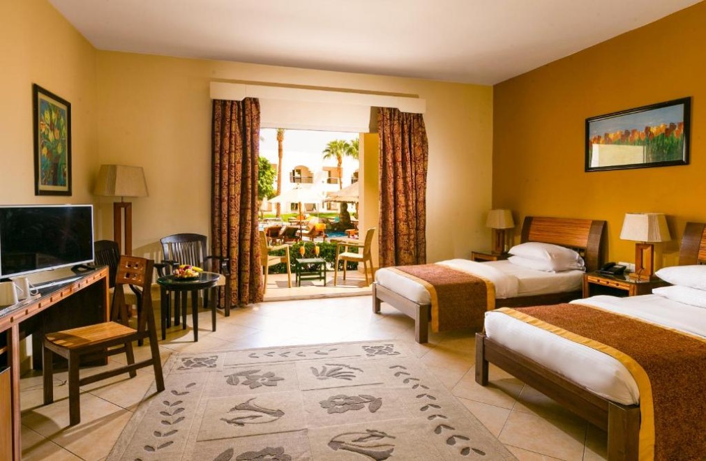 Family room with two single beds, pool view balcony, and wooden furniture