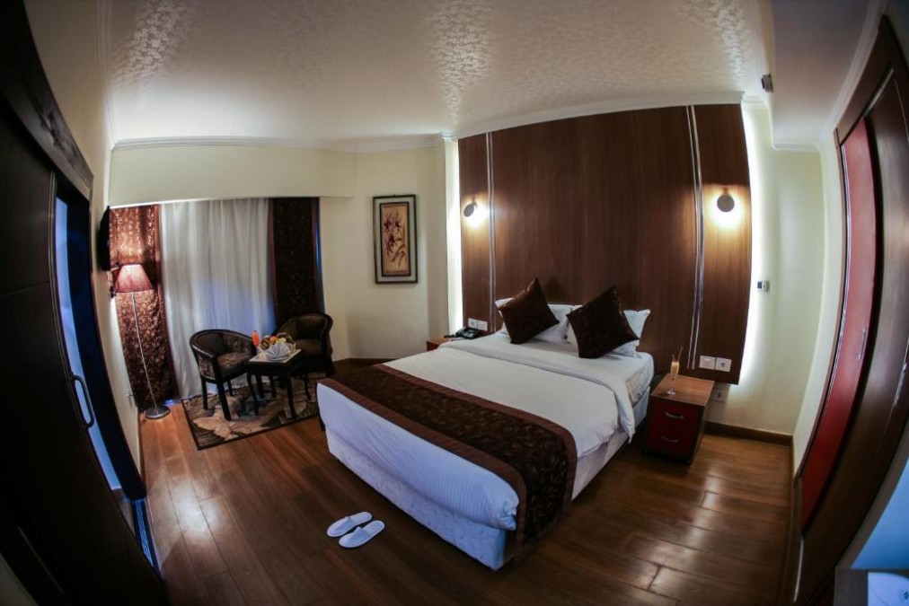 Double room with bed, small table and chairs, and floor-to-ceiling curtains.