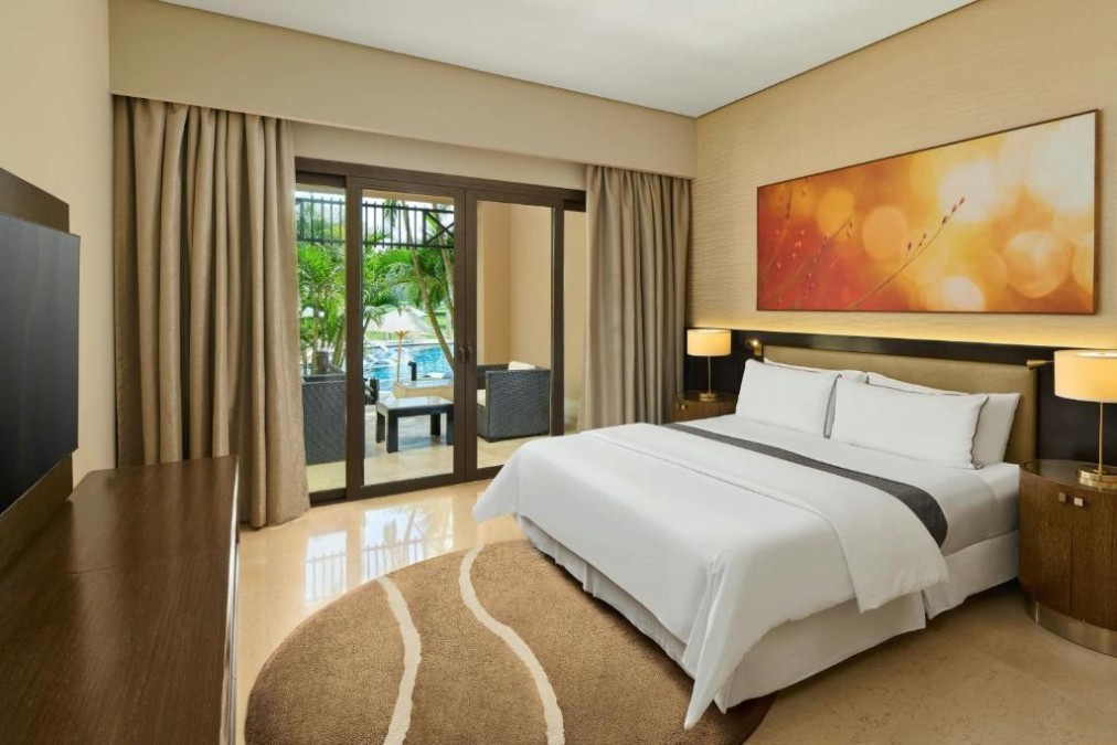 Guest room with king bed, bedside lamps, and sliding doors to a terrace.