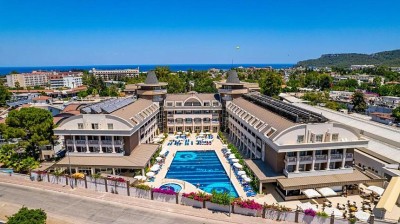 Aerial view of hotel complex with outdoor pool, sun loungers and surrounding town.