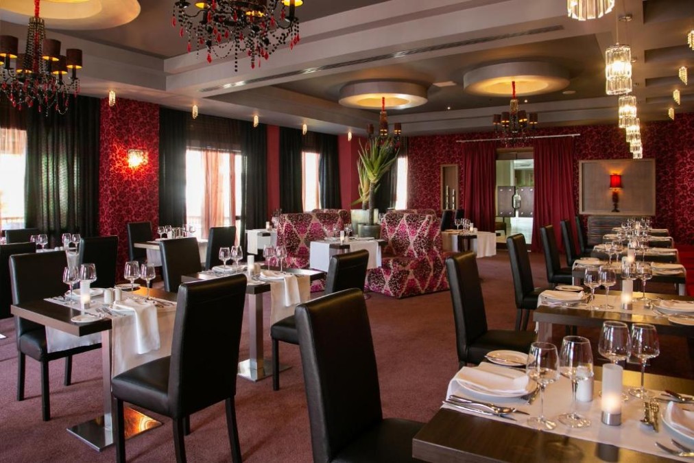 Restaurant dining room with set tables, chandeliers and patterned seating.