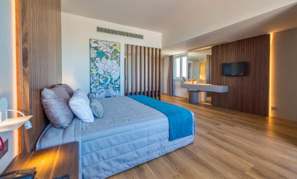 Spacious guest room with double bed, desk and wood-paneled walls.