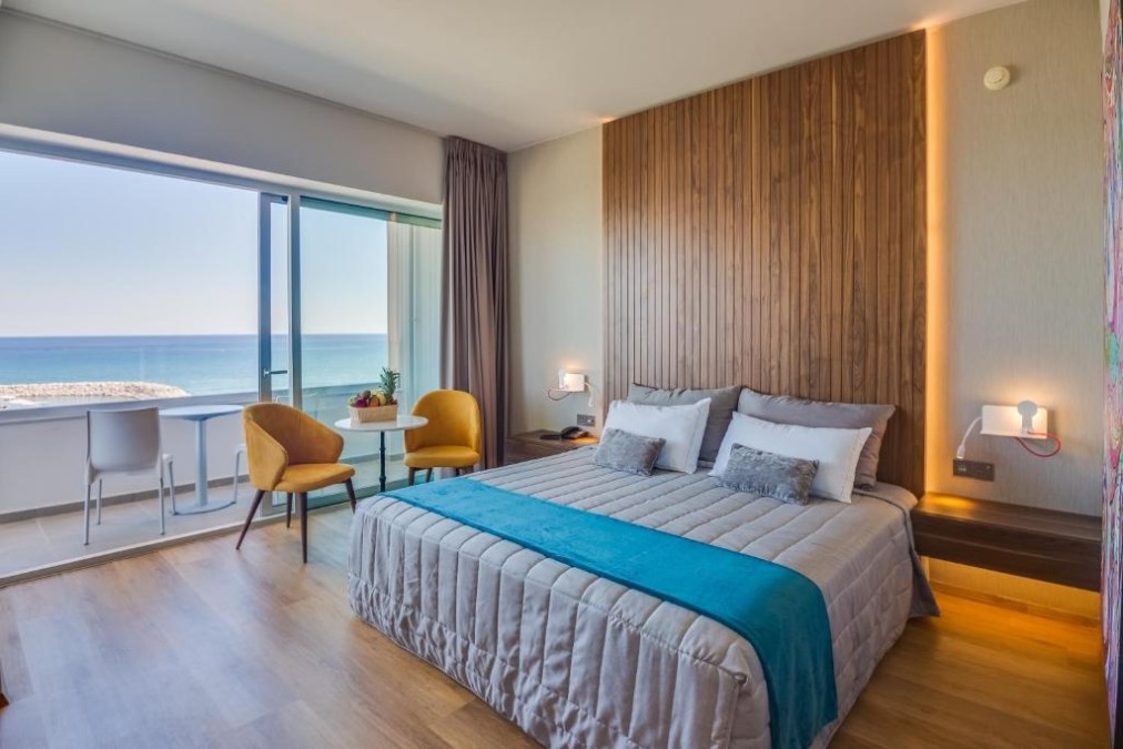 Guest room with double bed, balcony seating and sea view.