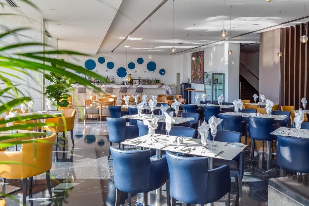 Restaurant dining area with bar, table settings and lounge seating.