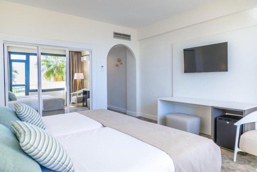 Guest room with bed, TV, desk and mirrored sliding doors.