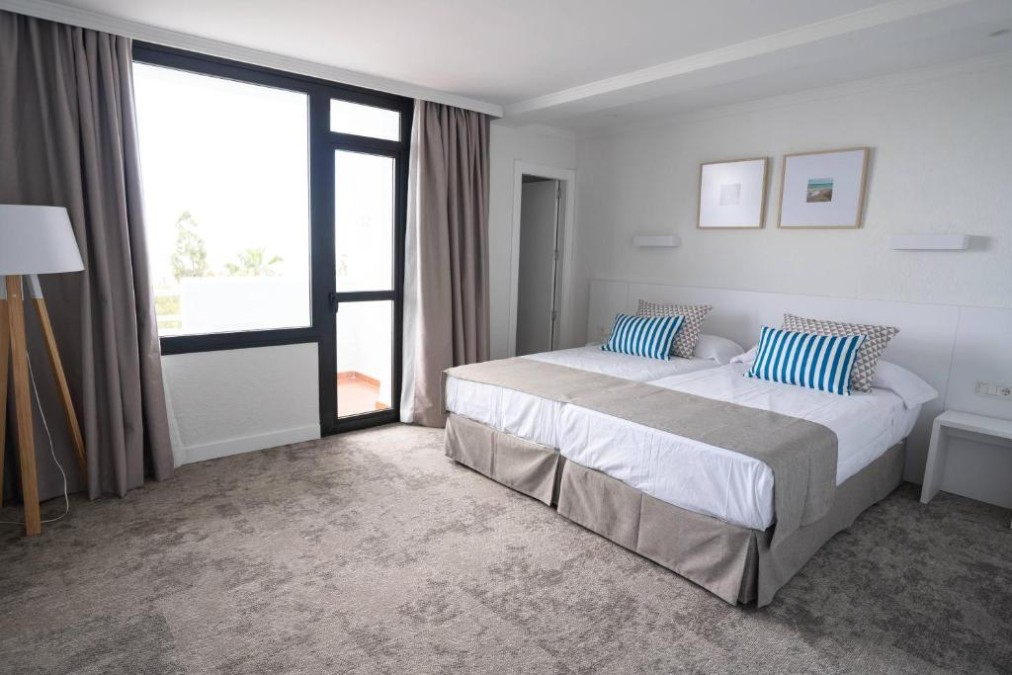 Bright guest room with a double bed, large window and balcony door.