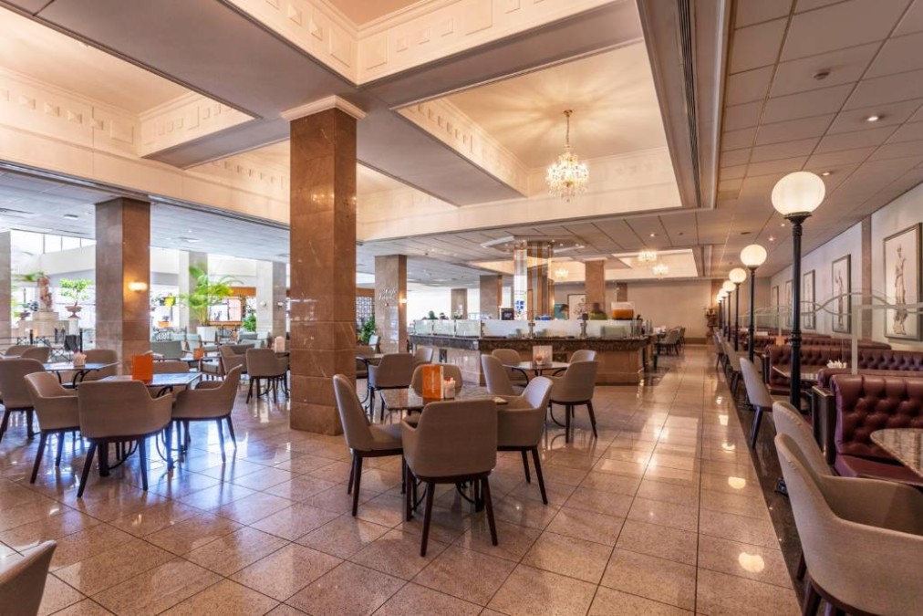Spacious hotel restaurant with dining tables, booths and buffet counters.