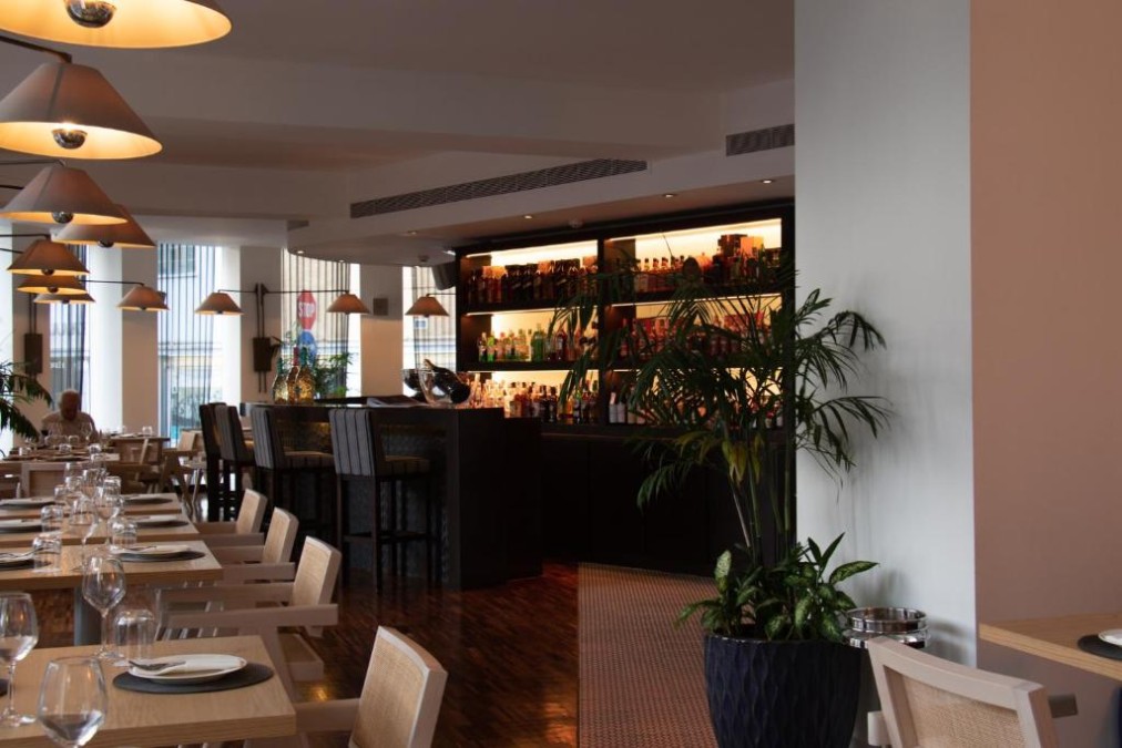 Restaurant and bar area with dining tables, pendant lights and backlit shelves.