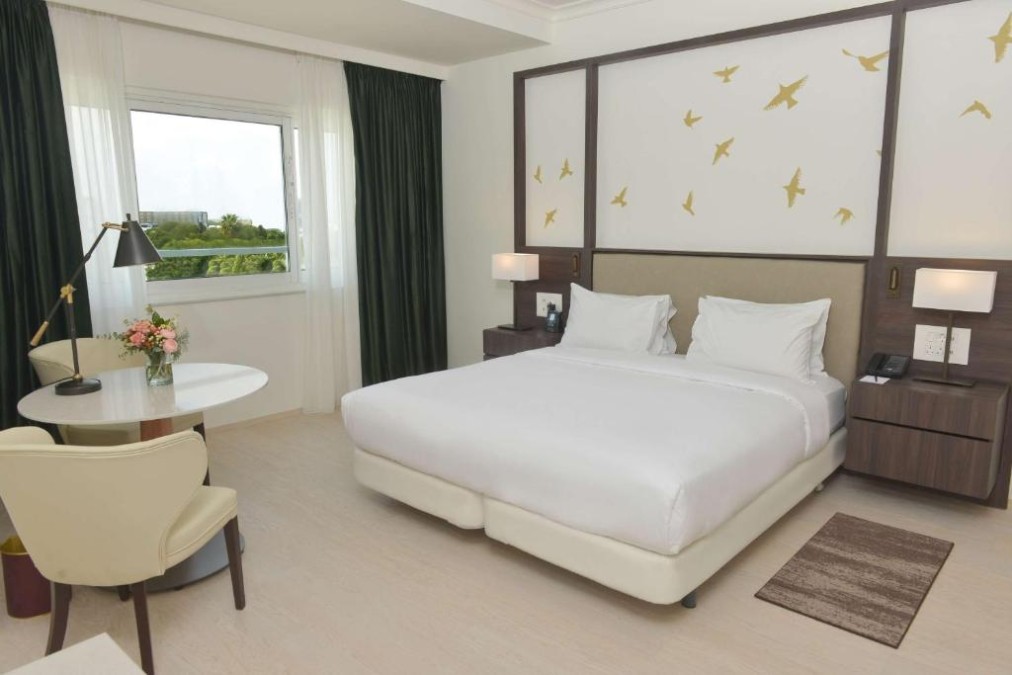 King guest room with desk, armchair and large window.