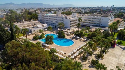 Aerial view of the hotel building, pool area and surrounding city.
