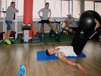 Hallentraining mit Athleten, die Gymnastikbälle und stationäre Fahrräder während des Workouts nutzen