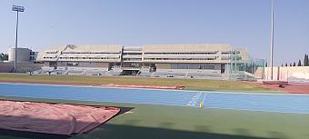 Weitwinkelansicht eines Sportkomplexes mit blauen und roten Laufbahnen sowie zentralem Rasenfeld