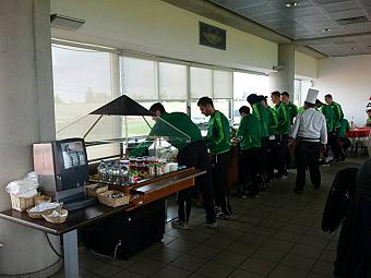 Athleten in grüner Sportkleidung wählen Mahlzeiten vom Buffet während des Trainingslagers