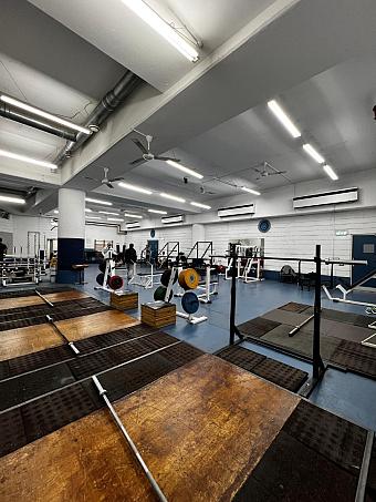 Geräumiger Kraftraum mit Holzplattformen, Langhanteln und Racks für Kraft- und Konditionstraining