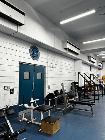 Innen-Fitnessstudio mit Hantelbanken, Racks und blauem Boden, genutzt für das Krafttraining von Athleten