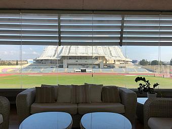 Loungebereich mit Sofas und großem Fenster mit Blick auf das Stadion und die Laufbahn