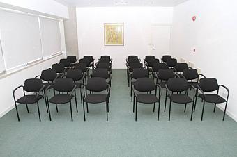 Konferenzraum mit Reihen schwarzer Stühle, angeordnet für ein Teammeeting oder Briefing