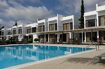 Modernes Resort mit weißen zweistöckigen Gebäuden, die einen klarblauen Swimmingpool umgeben