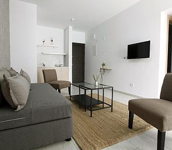 Lounge-Bereich mit grauem Sofa, Sesseln und Fernseher, schlicht und modern eingerichtet