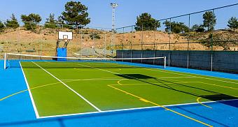 Kombination aus Tennis- und Basketballplatz mit grünen und blauen Spielflächen und Umzäunung