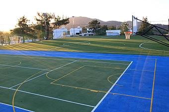 Blaue und grüne Außenplätze für Basketball und Fußball mit Bergen im Hintergrund
