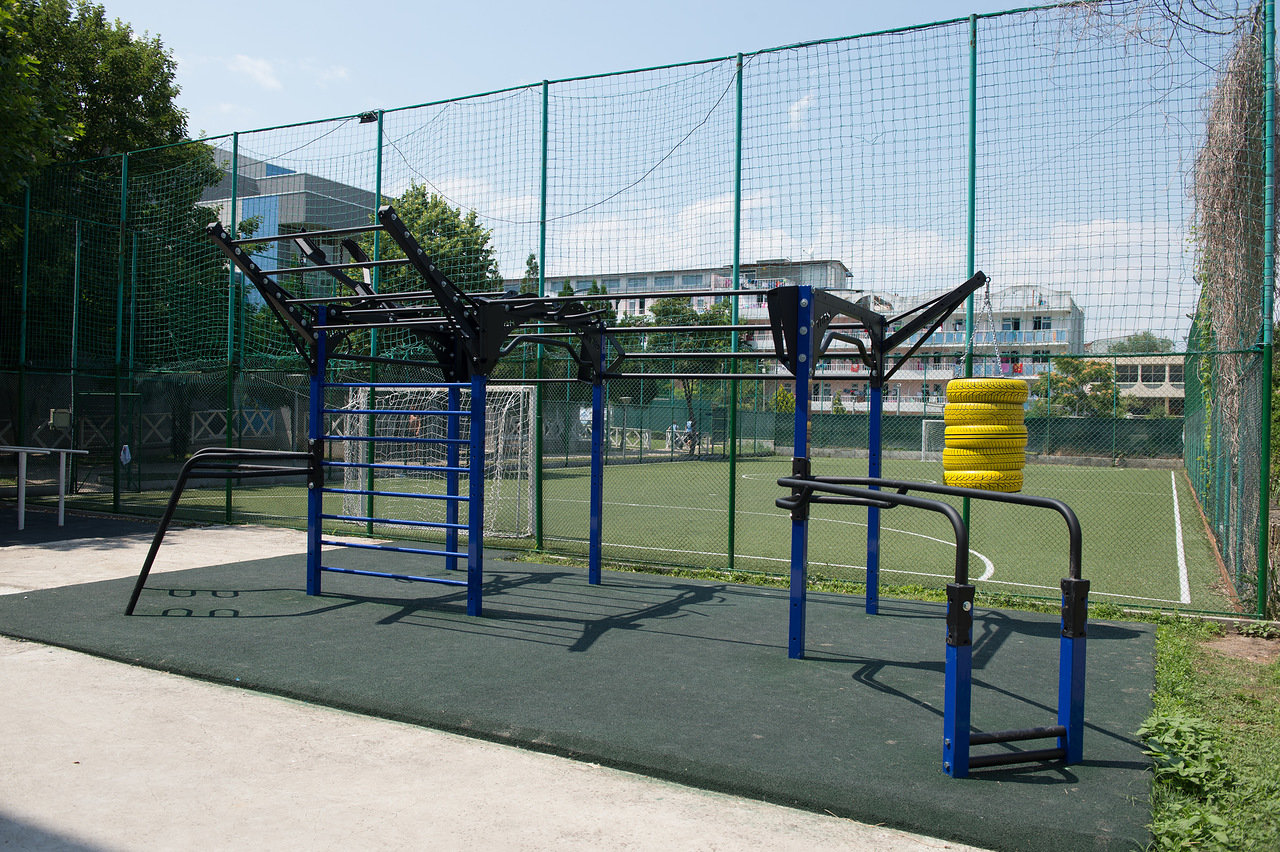 Outdoor fitness area with pull-up bars and obstacles, designed for strength drills during training camp