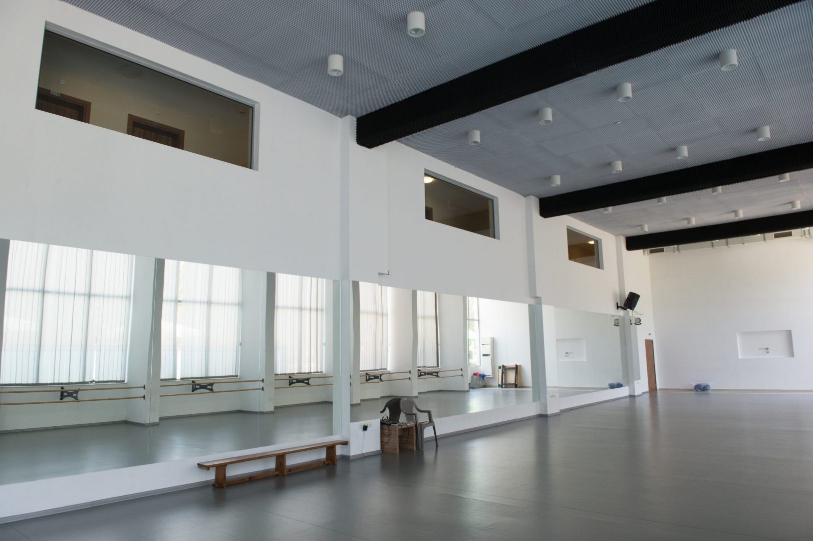 Spacious mirrored studio with benches and natural light, used for coaching and practice sessions