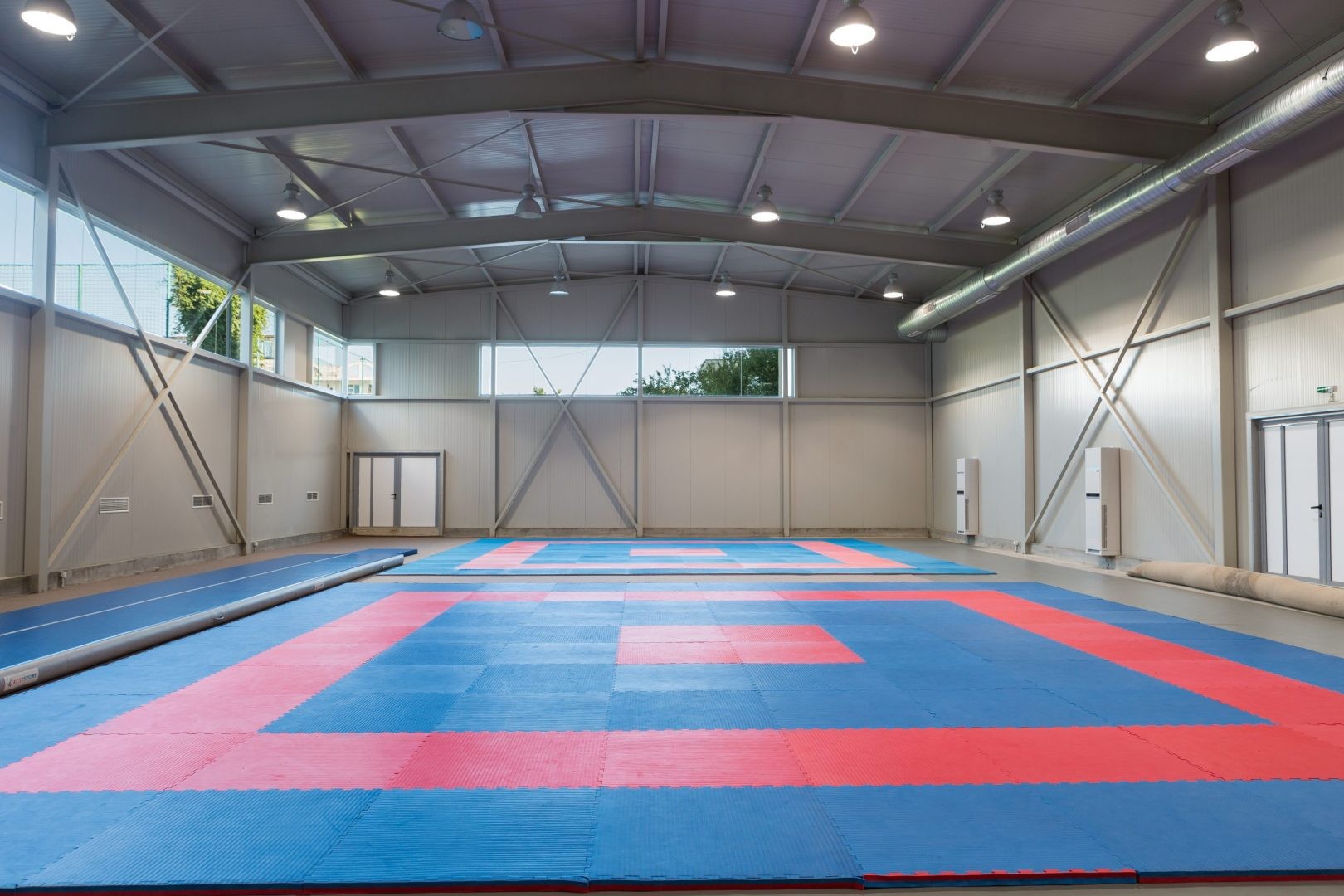Indoor training hall with red and blue mats, prepared for martial arts or gymnastics training camp